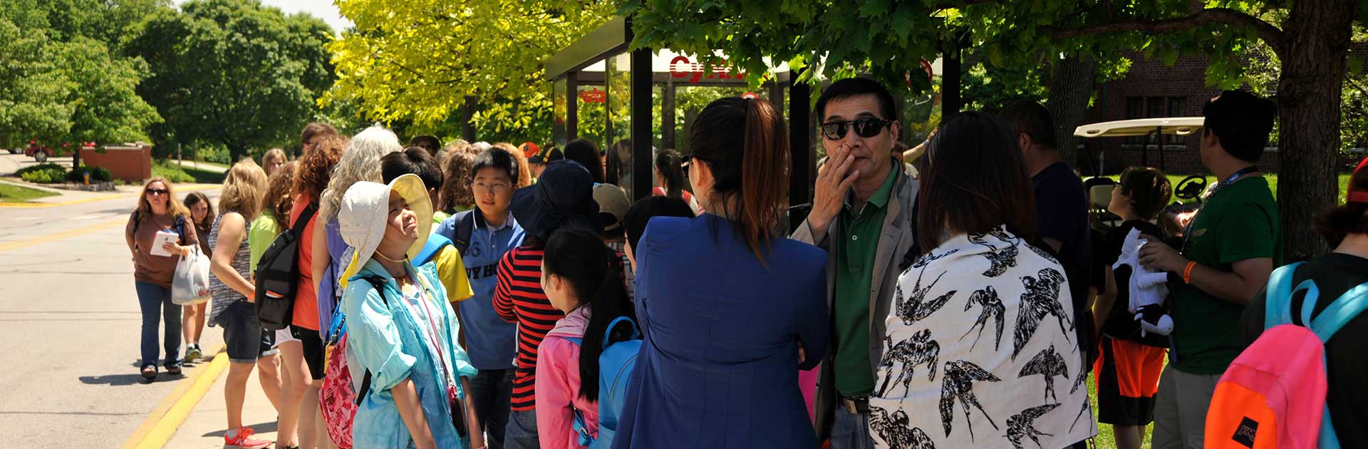 Large crowd of passengers wait for bus at Union Drive bus stop on ISU campus.