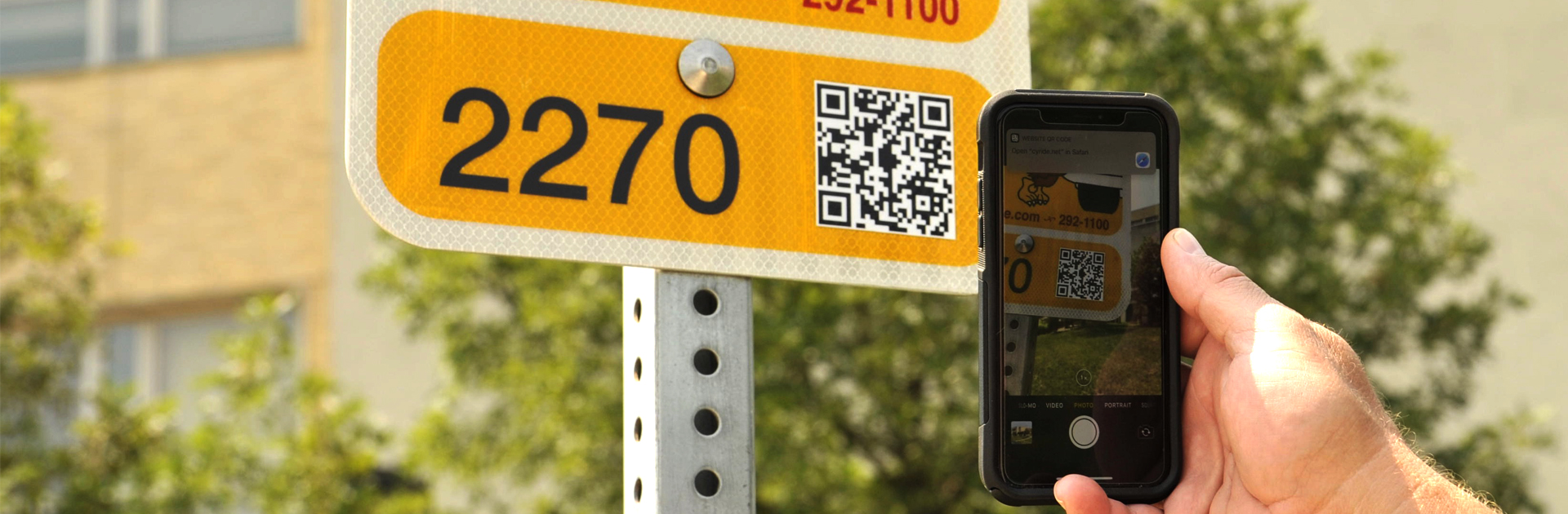 NextBus bus stop sign with person scanning QR code to obtain real-time bus information